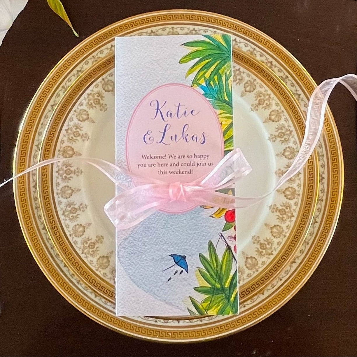 Dining table setting with floral arrangement, plates, cutlery, and glasses on a dark surface.